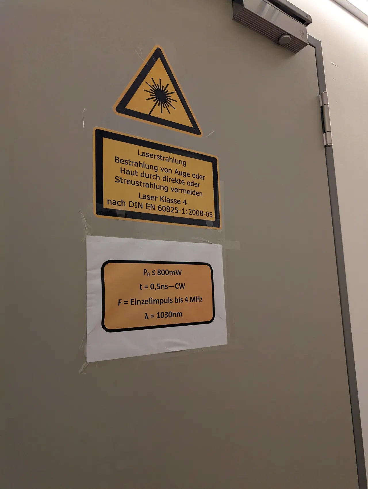 A lab door at DESY with a yellow warning sign in German for class 4 laser radiation, and a note giving up to 800 mW at 1030 nm.